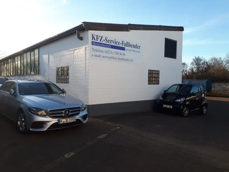 Werkstattgebäude von Kfz-Service Fassbender mit dem Schild „KFZ-Service-Faßbender – Meisterbetrieb, speziell Mercedes“; davor eine Mercedes E-Klasse und ein smart.